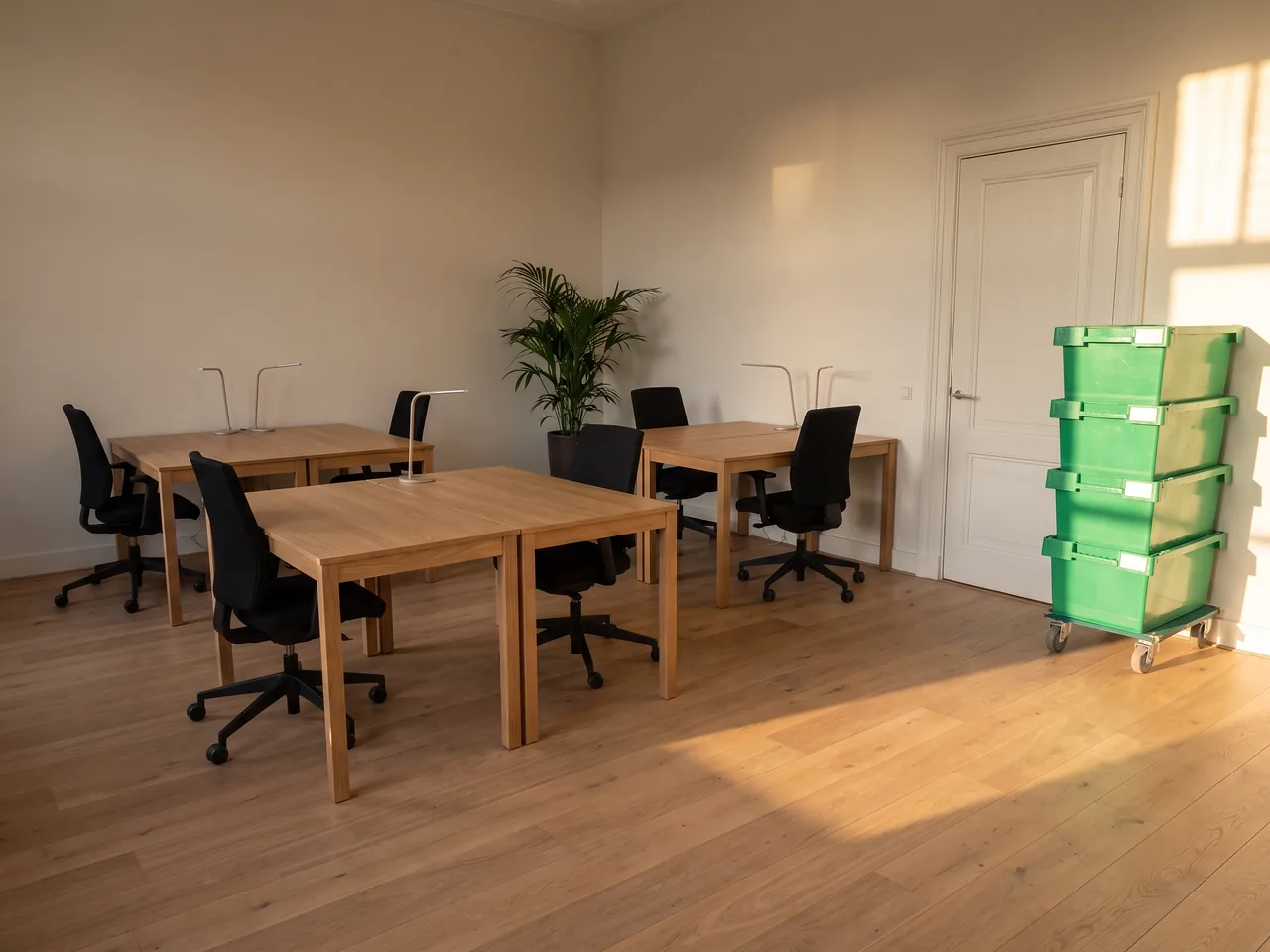 Ingericht kantoor met werkplekken en naast de deur een stapel groene verhuiskratten op een rolplateau.