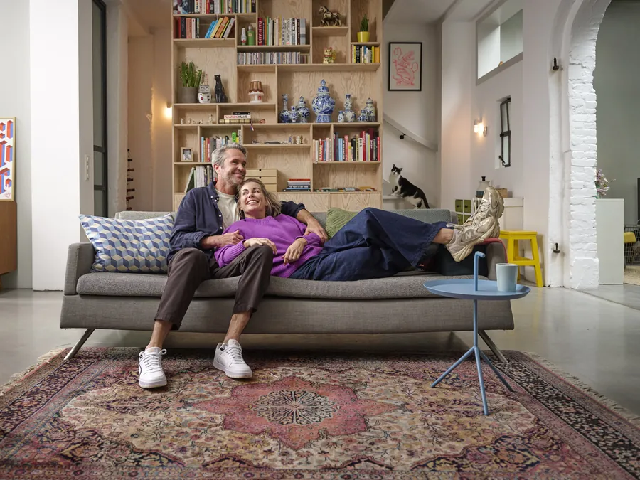 Stel ontspannen op de bank in een ingerichte woonkamer, campagnebeeld van Erkende Verhuizers