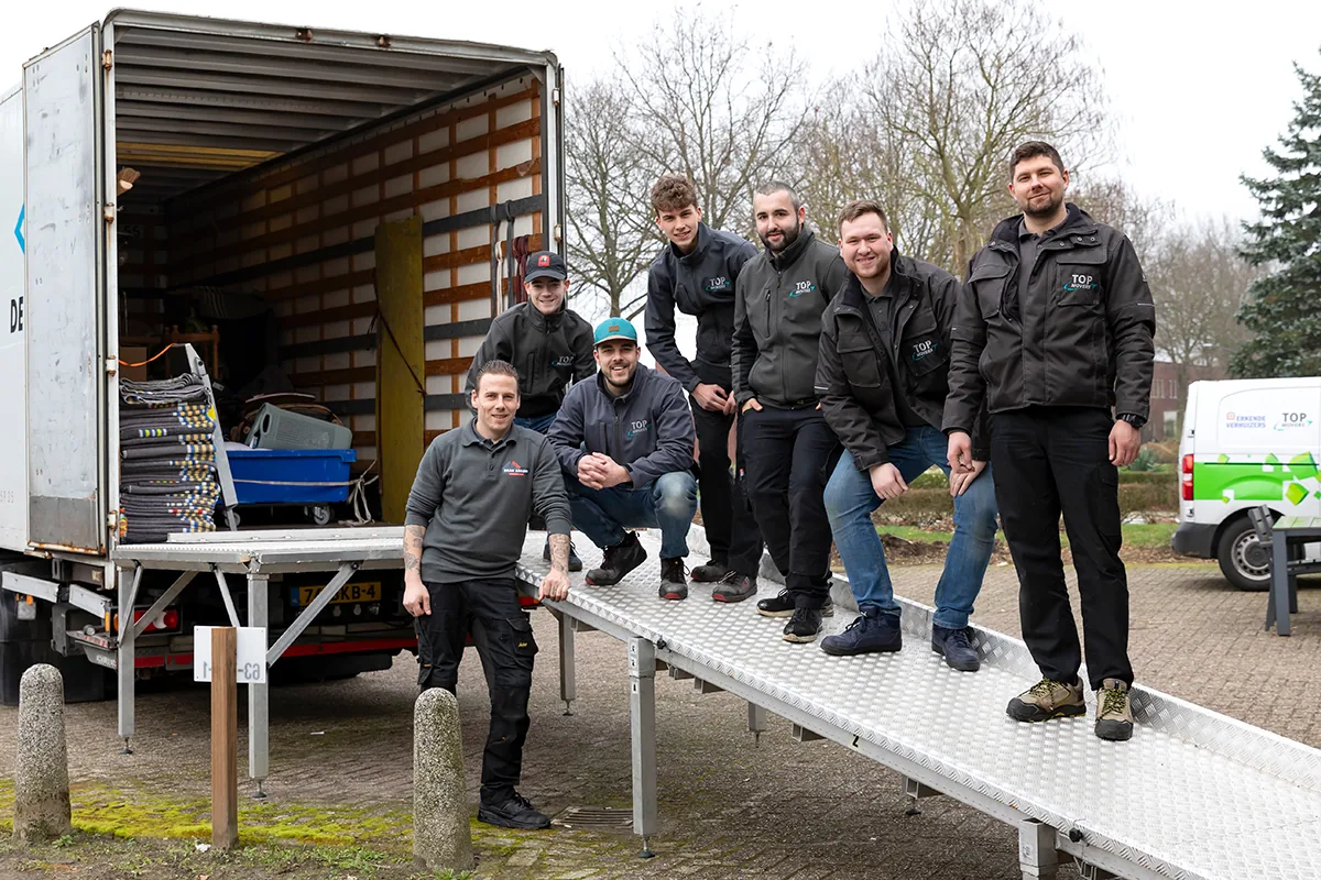 Het verhuisteam van De Bresser op de laadklep van een verhuiswagen