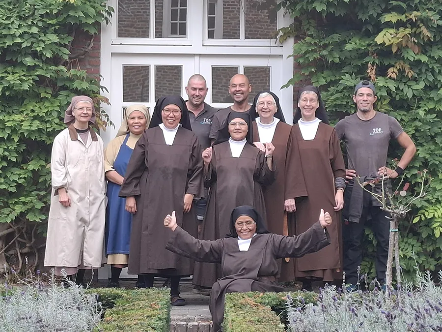 Drie verhuizers samen met de zusters van een klooster voor het kloostergebouw