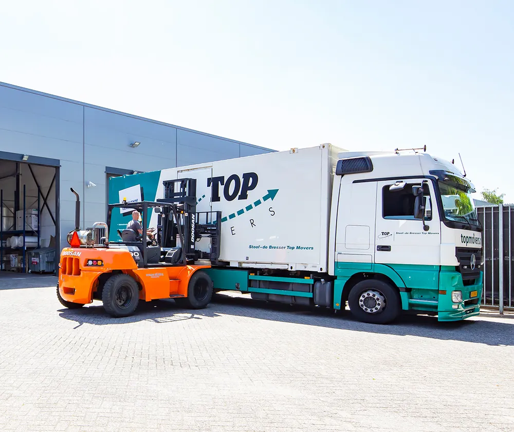 Top Movers-wagen met heftruck op een bedrijfsterrein.