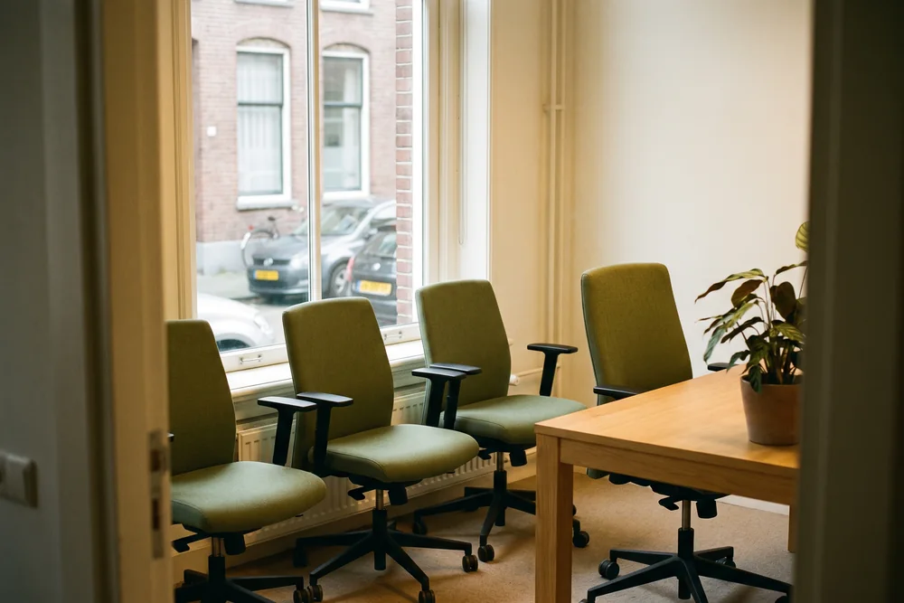 Vier opgeknapte bureaustoelen met nieuwe groene stoffering op een rij bij het raam, klaar voor hergebruik
