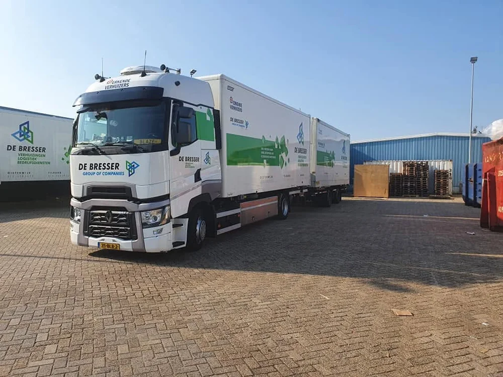 Vrachtwagen met aanhanger van De Bresser, met het logo van Erkende Verhuizers op de cabine
