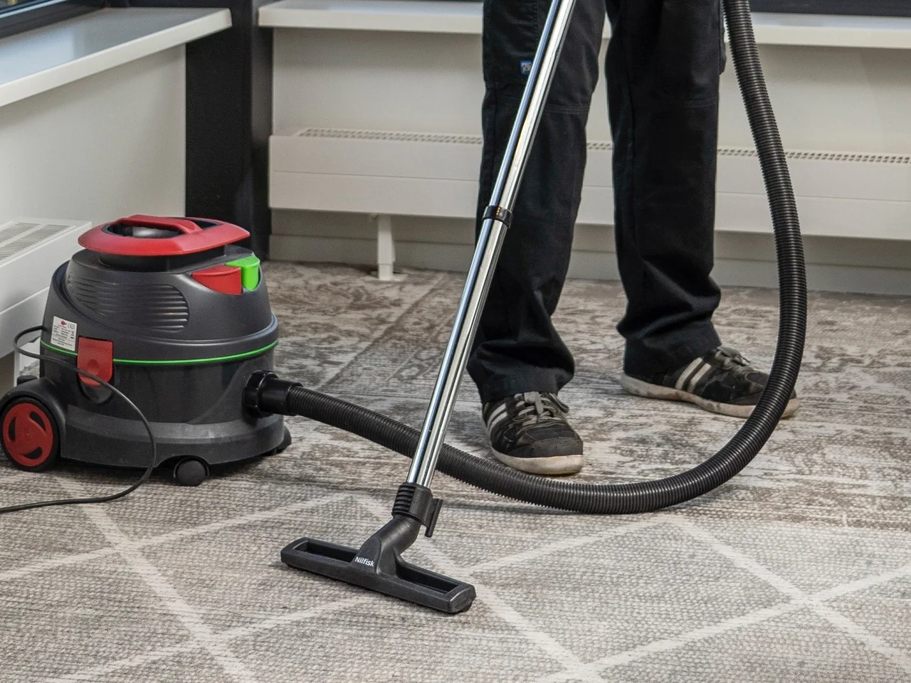 Medewerker van De Bresser zuigt het tapijt van een kantoor