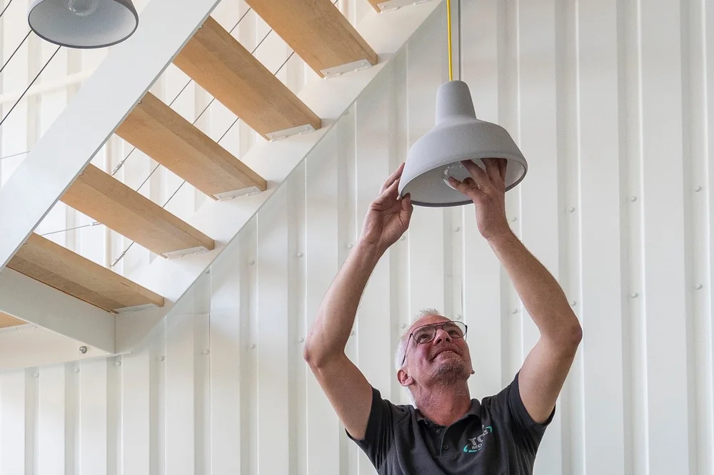 Verhuizer van De Bresser hangt een lamp op onder een trap