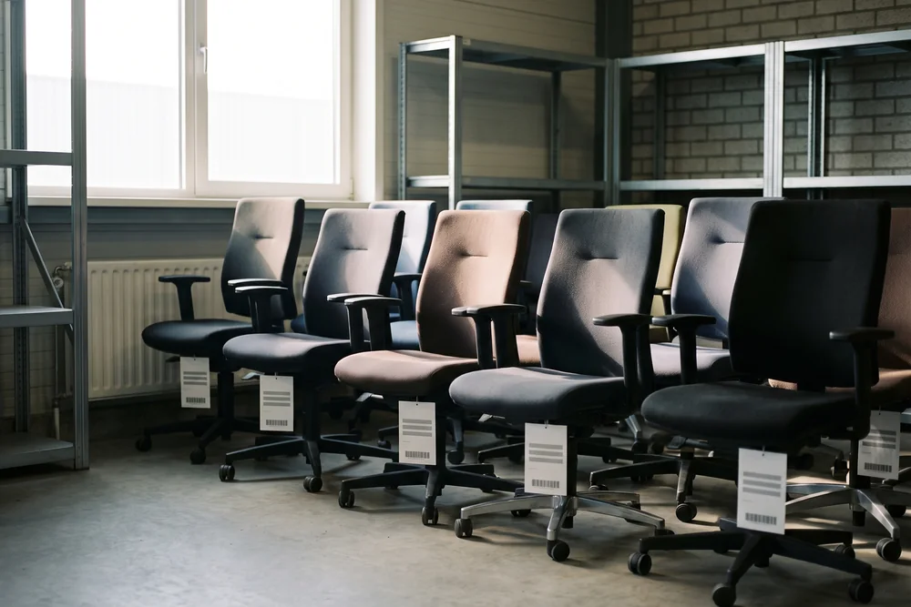 Rij gebruikte kantoorstoelen met labels in de hal, klaar voor een volgende gebruiker