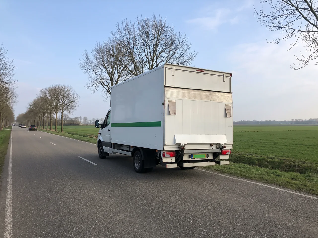 Verhuiswagen onderweg op een rechte polderweg