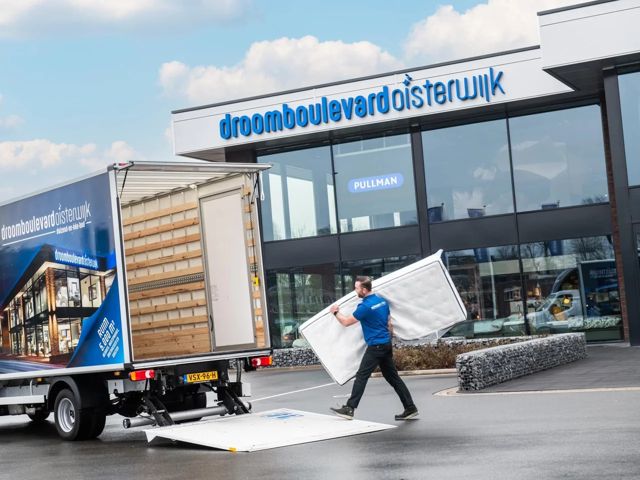 Man draagt een matras van de laadklep van een bakwagen naar de winkel van Droomboulevard Oisterwijk