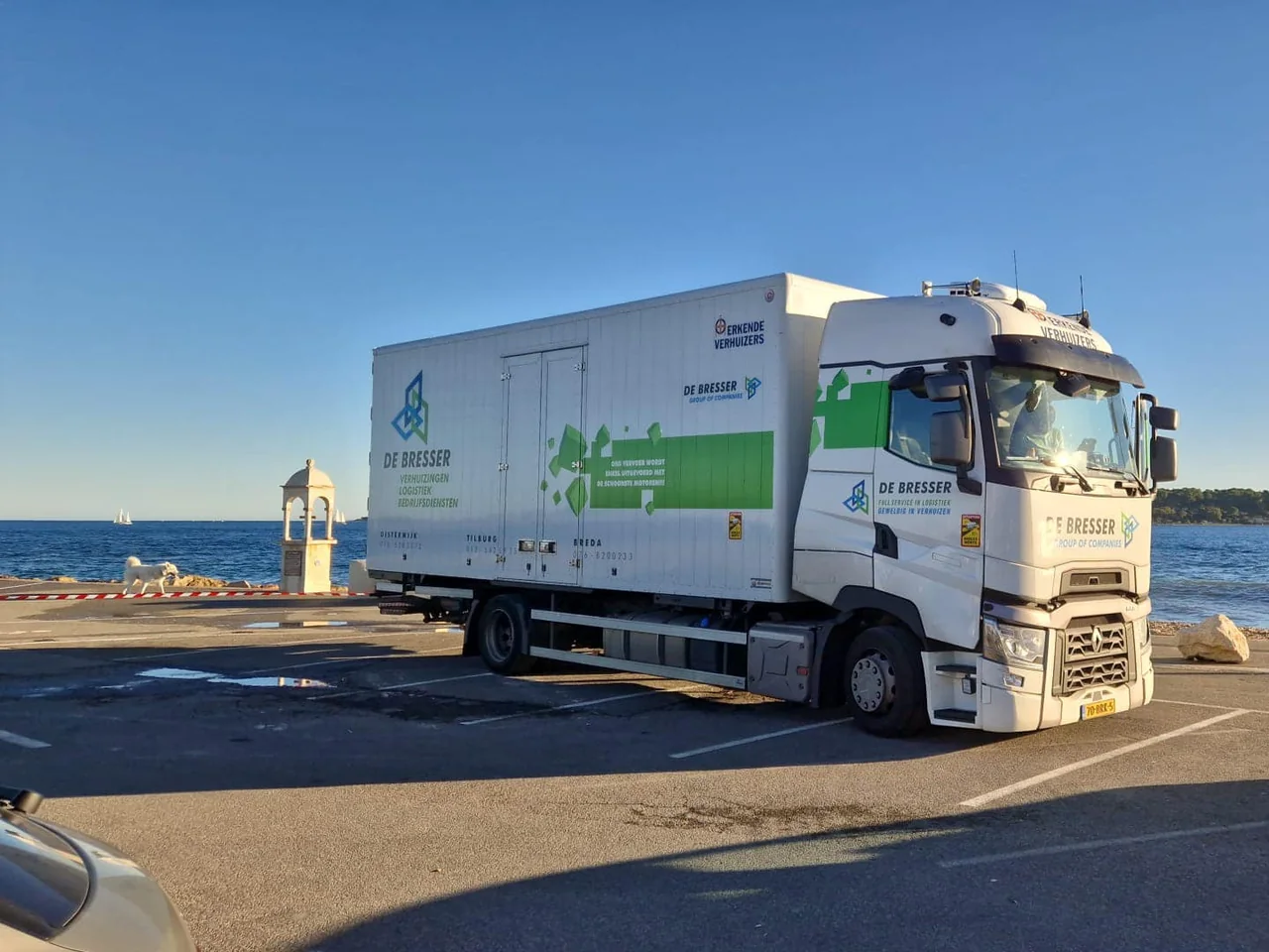 Vrachtwagen van De Bresser op een parkeerplaats aan zee in Frankrijk, onder een strakblauwe lucht