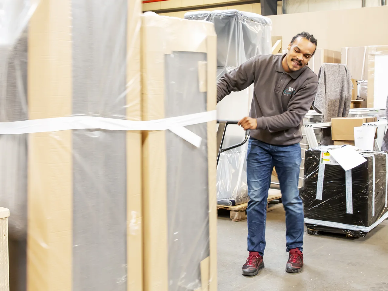 Medewerker van De Bresser met een ingepakt meubelstuk in de loods