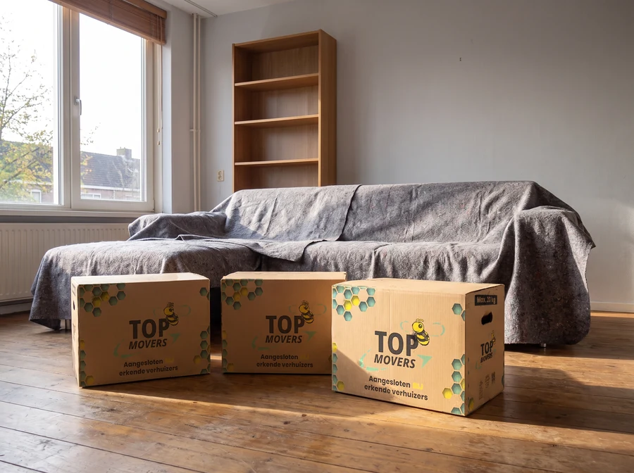 Top Movers-verhuisdozen in een woonkamer met een afgedekte bank