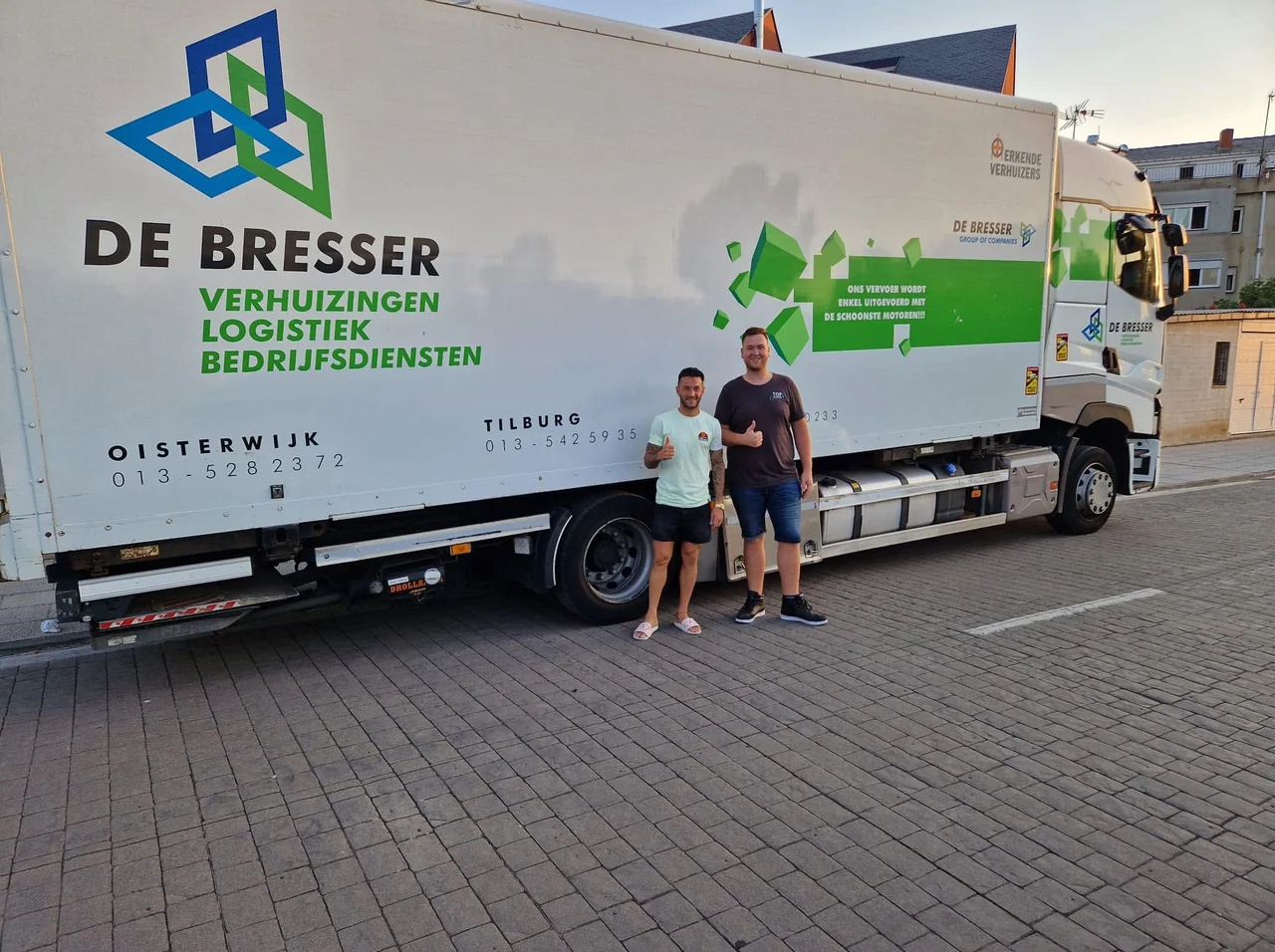 Vrachtwagen van De Bresser met het logo van Erkende Verhuizers in een woonstraat, met twee mannen ervoor